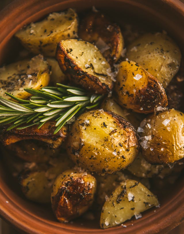 roast potatoes with salt, rosemary and ev olive oil in a terracotta bowl